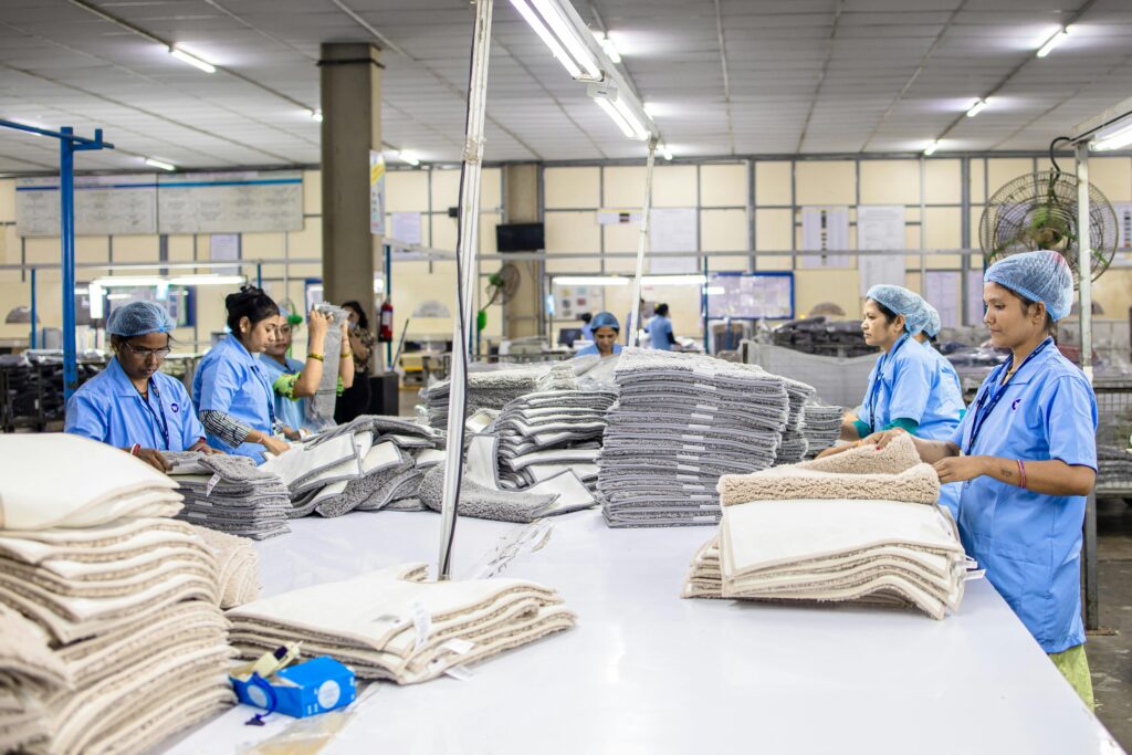 A team of textile workers sorting and folding fabrics in a well-lit factory setting.